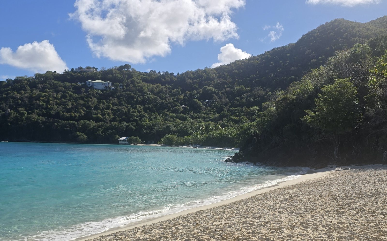 Hawksnest Beach with green hillside and turquoise water